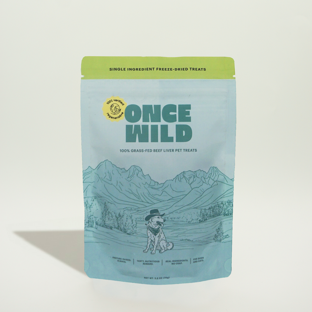 A stand-up pouch of Once Wild dog food treats on a clean white background. The package is light blue with a lime green top band, featuring the brand name 'ONCE WILD' in large teal letters and an illustration of a dog in a landscape with mountains.