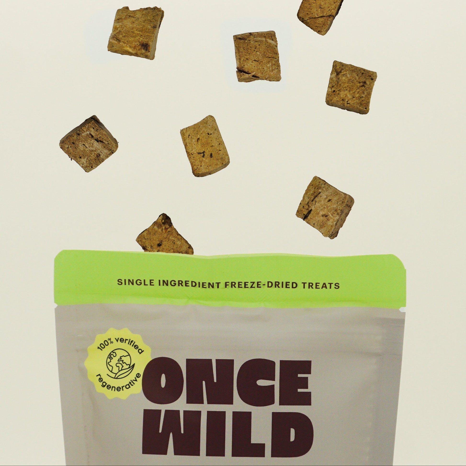 Once Wild single ingredient freeze-dried treats packaging with scattered treats on a beige background