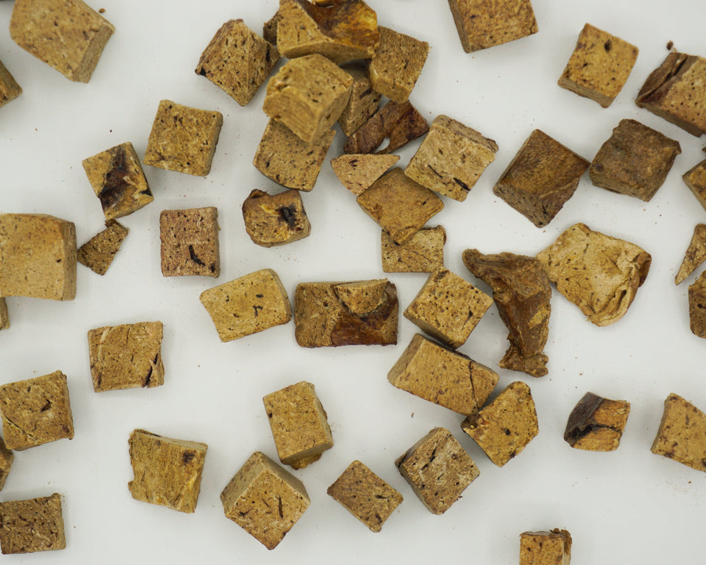 Bison liver treats scattered on a white surface