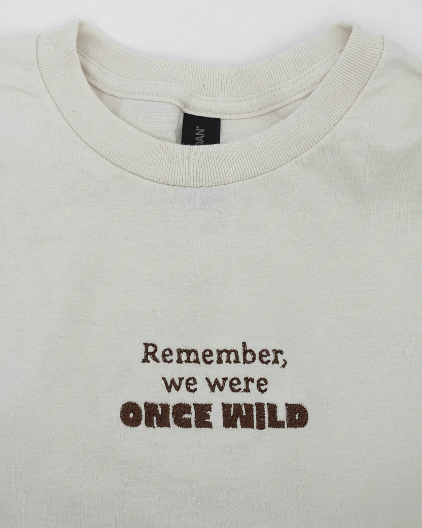 Beige shirt with embroidered text 'Remember, we were once wild' on a white background